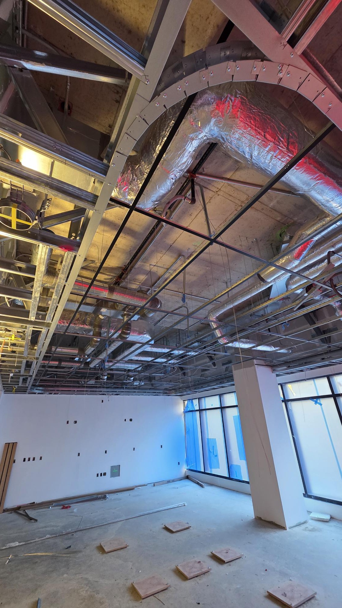 Open suspended T-bar ceiling grid beneath exposed services during Rambo’s Slocan installation.