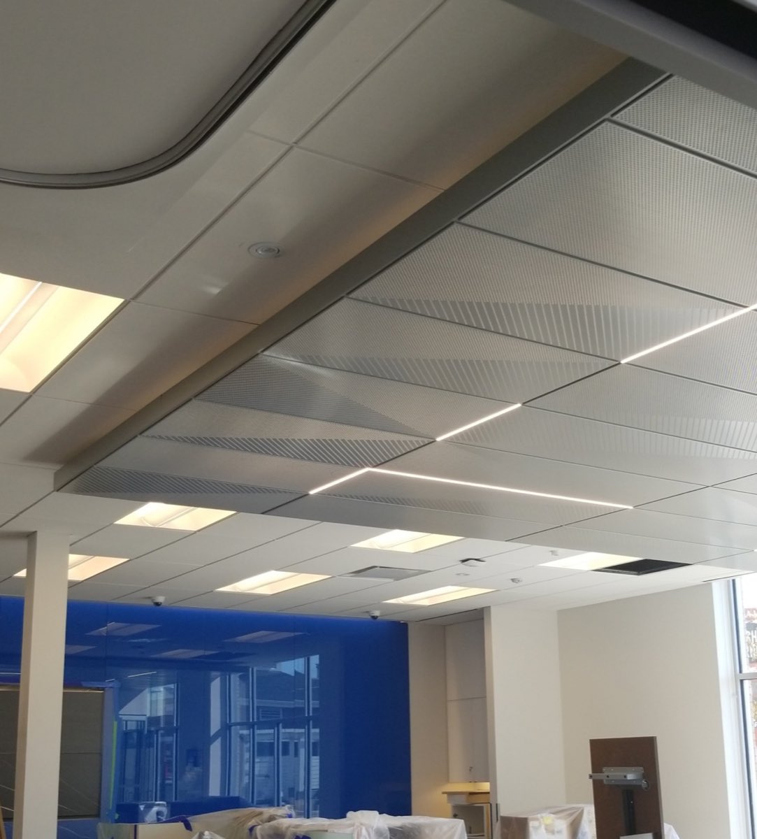 Perforated metal ceiling panels with integrated linear lighting