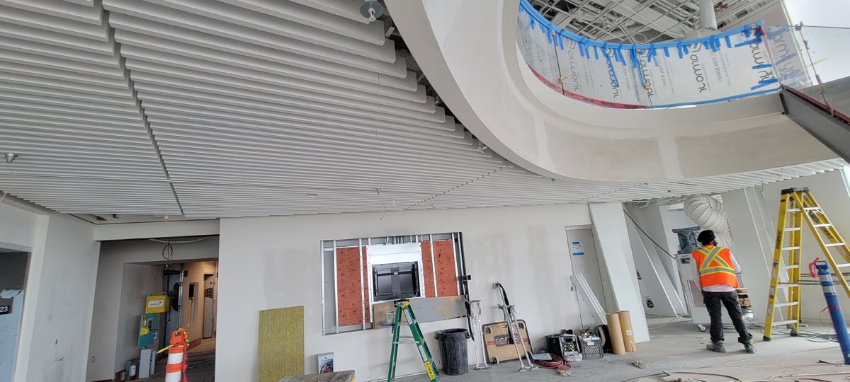 Linear white ceiling baffles around a curved opening