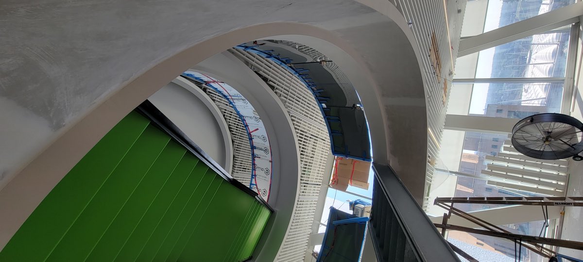 Coloured ceiling element and white baffles in a multi-level interior